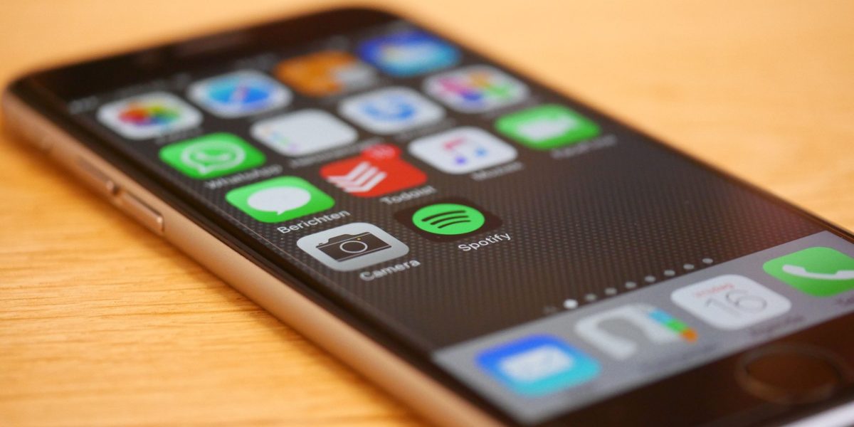 Ahşap masa üzerinde uygulama ikonlarını gösteren bir akıllı telefon ekranı